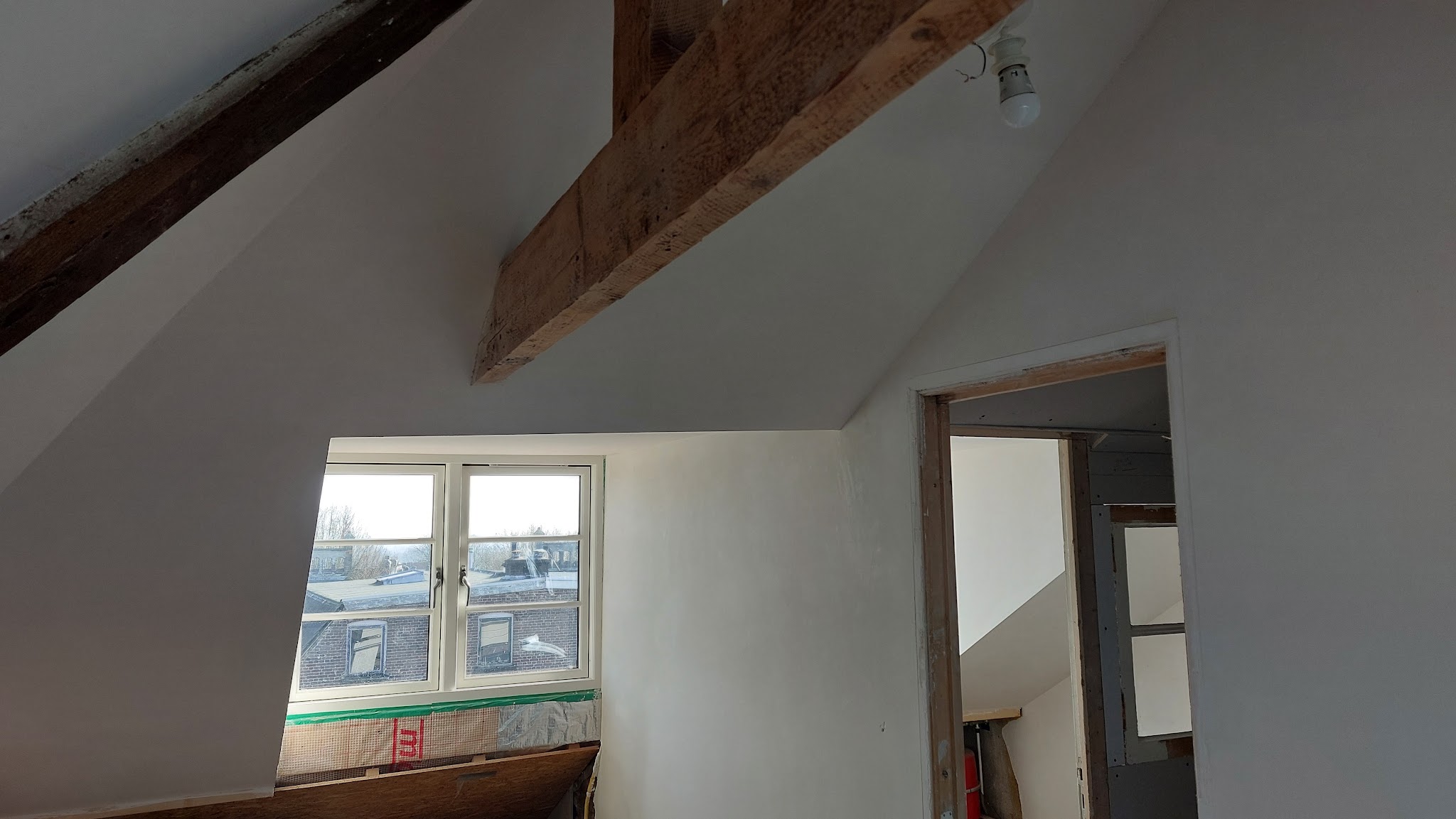 Gestucte zolderkamer met houten balken en dakraam