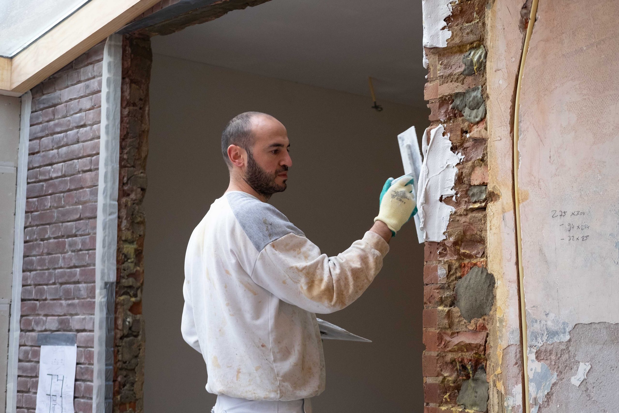Murat stuct een bakstenen muur naast een deuropening